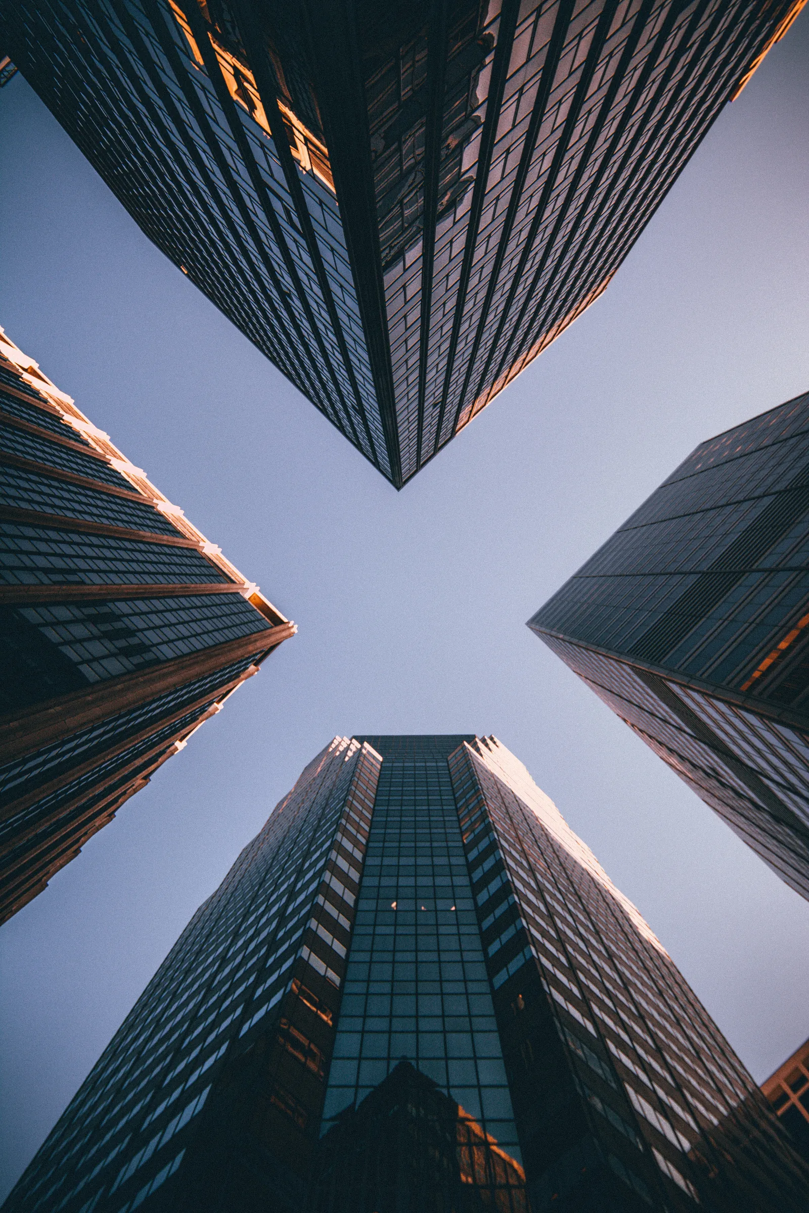Looking up between city towers into a clear sky